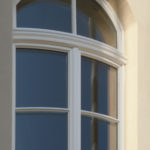 weißes Bauchbogenfenster mit Oberlicht und Zierleisten sowie Vogelspikes